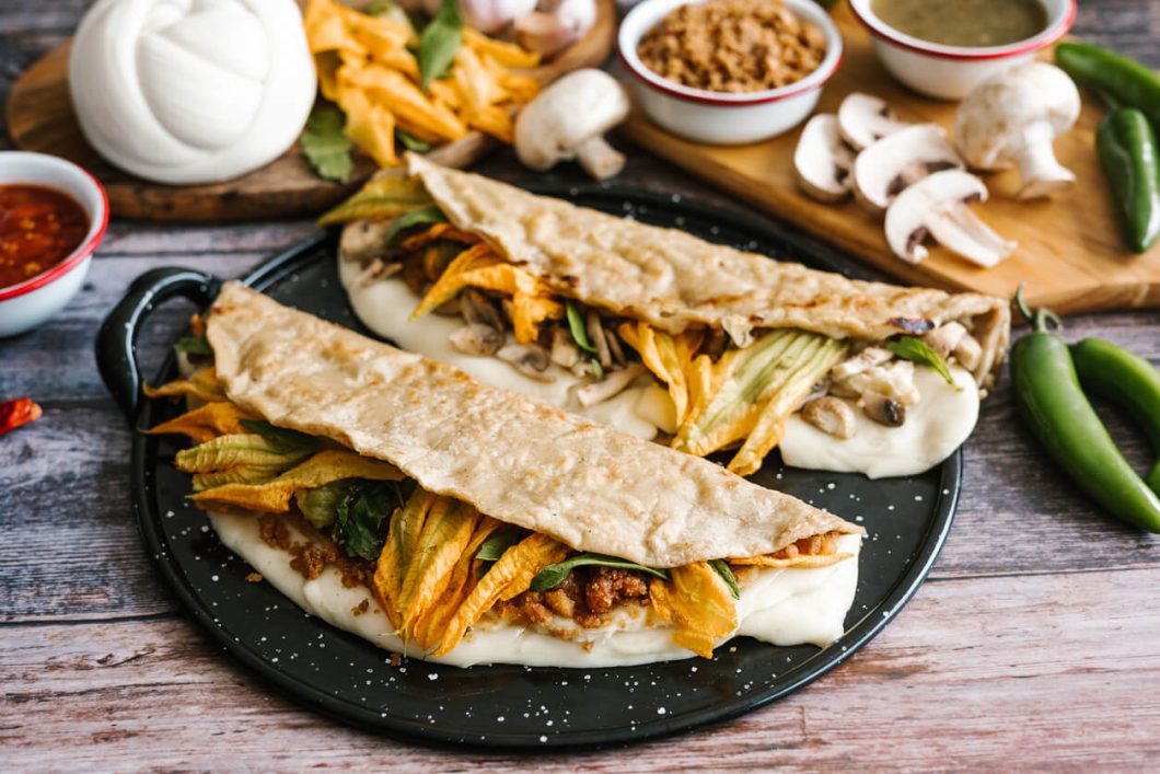 The combination of textures from the crispy vegetarian chicharrón, the soft mushrooms, and the gentle squash blossoms, all held together with melted cheese, makes these quesadillas a satisfying meal with an elegant touch.