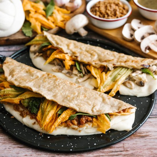 The combination of textures from the crispy vegetarian chicharrón, the soft mushrooms, and the gentle squash blossoms, all held together with melted cheese, makes these quesadillas a satisfying meal with an elegant touch.